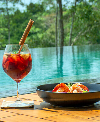 A-La Carte dish of shrimp and a Mocktail placed beside the Salt Water infinity pool at Haritha Villas and spa